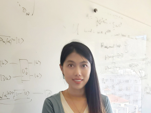 Di Fang standing in front of white board of equations